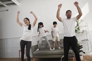 feliz bem-estar família tailandesa asiática, pais e filhos são divertidos jogando bambolê juntos, treinamento físico e exercícios saudáveis na sala de estar branca, estilo de vida doméstico e atividade de fim de semana. foto