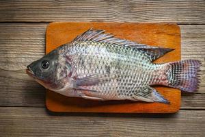 tilápia em fundo de tábua de madeira, peixe tilápia cru fresco da fazenda de tilápia foto