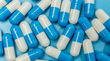 medicação, pílula cápsula azul e branca sobre fundo azul foto