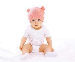 retrato de um doce bebê sentado com o chapéu de malha rosa