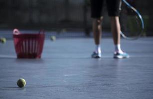 tênis, cesta vermelha e um jogador amador foto