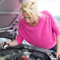 mulher inspecionando o motor do carro quebrado. foto
