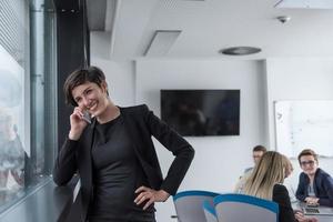 mulher elegante usando o celular pela janela no prédio de escritórios foto