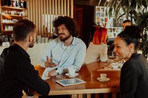 um grupo de amigos em um café, e entre eles está um tablet. foto