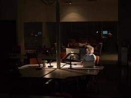 homem trabalhando no computador no escritório escuro foto