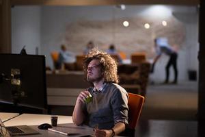 homem trabalhando no computador no escritório escuro foto