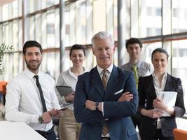 retrato do empresário sênior como líder com funcionários em segundo plano foto