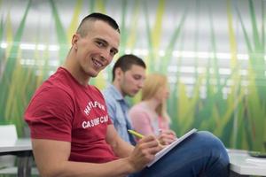 estudante do sexo masculino tomando notas em sala de aula foto