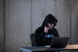 hacker talentoso usando laptop enquanto trabalhava no escritório escuro foto