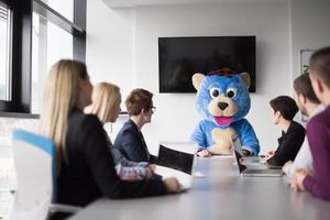 chefe vestido de urso se divertindo com empresários no escritório da moda foto