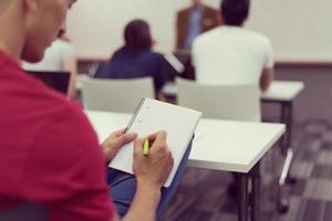 estudante do sexo masculino tomando notas em sala de aula foto