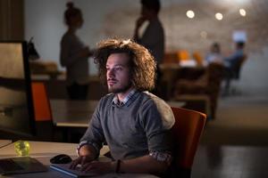 homem trabalhando no computador no escritório escuro foto