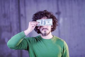 homem de negócios segurando notas de dólar americano sobre os olhos foto