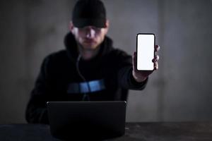 hacker criminoso usando laptop enquanto trabalhava no escritório escuro foto