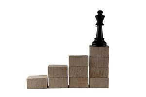 peças de xadrez em cima de um bloco de madeira. o conceito de sucesso de um líder foto