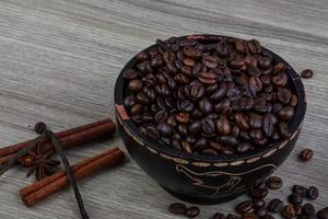 grãos de café em uma tigela com fundo de madeira foto