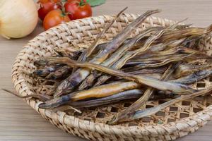 peixe seco em uma cesta em fundo de madeira foto