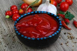 ketchup de tomate em uma tigela no fundo de madeira foto