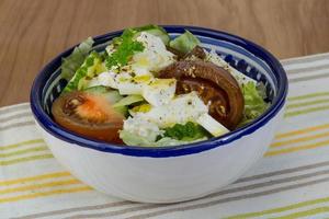 salada grega em uma tigela sobre fundo de madeira foto