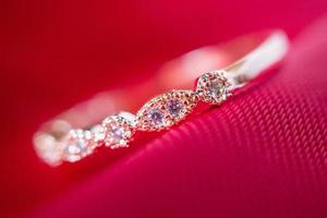 anel de ouro rosa de luxo de joias com pedra preciosa de safira no fundo de textura de tecido vermelho foto