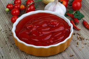 ketchup de tomate em uma tigela no fundo de madeira foto