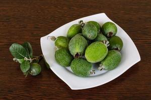 fruta feijoa no prato e fundo de madeira foto