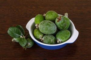 fruta feijoa em uma tigela com fundo de madeira foto