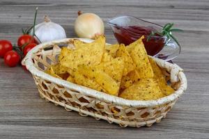 nachos em uma cesta em fundo de madeira foto