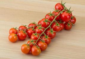 tomate cereja em fundo de madeira foto