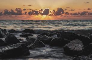 praia rochosa ao pôr do sol foto
