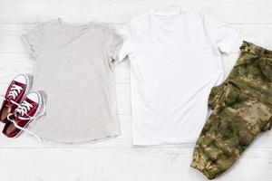 camiseta masculina e feminina branca e tênis. maquete de t-shirt plana com acessórios de verão. roupa para mulheres e homens em fundo de piso de madeira. copie o espaço. modelo de tela em branco. foto