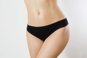 nutrição saudável e conceito de saúde da barriga. close-up de barriga lisa de mulher. calcinha feminina modelo em branco preto com espaço de cópia e mock up. vista frontal. imagem recortada, bodycare feminino isolado em cinza foto