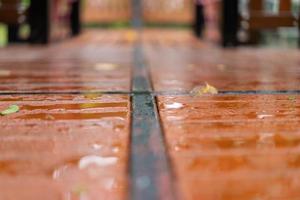 feche o piso de madeira molhado com folhas caídas no campo ao ar livre depois que a chuva vem. foto