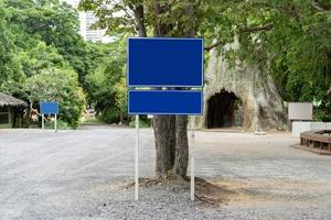 sinal de trânsito azul em lotes de estacionamento com árvore ao redor. caminhos de recorte foto