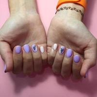 manicure de cores diferentes nas unhas. manicure feminina na mão no fundo rosa foto