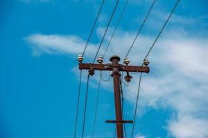 linhas elétricas de pólo elétrico saída de fios elétricos contra o céu azul da nuvem. foto