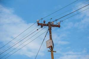 linhas elétricas de pólo elétrico saída de fios elétricos contra o céu azul da nuvem. foto