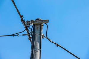 linhas elétricas de pólo elétrico saída de fios elétricos contra o céu azul da nuvem. foto