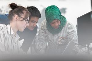 multiétnica equipe de negócios de inicialização mulher árabe vestindo um hijab na reunião no moderno escritório de plano aberto brainstorming interior, trabalhando no laptop e computador desktop. foco seletivo foto