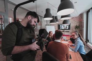 por trás da cena. cinegrafista gravando um grupo de jovens empresários multiétnicos trabalhando e se comunicando juntos em um escritório criativo. foco seletivo foto