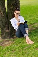 jovem lendo um livro no parque foto