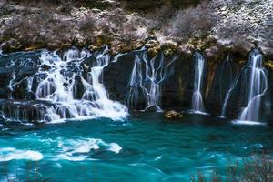 hraunfossar, uma cachoeira formada por riachos que fluem sobre hallmundarhraun, um campo de lava do vulcão situado sob a geleira langjokull, e despeje no rio hvita, islândia foto