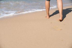 pegadas na areia da praia. mulher caminhando para o mar. foto