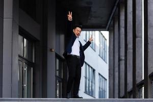 feliz e alegre empresário asiático dançando perto do escritório se alegra com a vitória e o sucesso foto