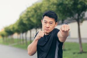 atleta asiático masculino demonstra rack de boxe durante corrida matinal e fitness foto