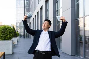 empresário asiático masculino se alegra segurando muito dinheiro em dinheiro obteve uma grande vitória e pagamento foto