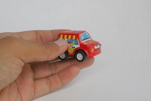 semarang, indonésia - 3 de dezembro de 2021, mão segurando o carro de brinquedo vermelho sobre fundo branco foto