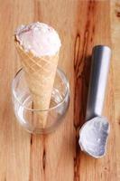 Cone de sorvete e utensílio de colher em fundo de madeira foto