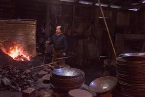 jovem ferreiro tradicional trabalhando com fogo aberto foto