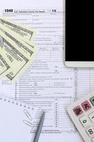 composição de itens contidos no formulário de imposto 1040. notas de dólar, caneta, calculadora, smartphone, clipe de papel e bloco de notas. hora de pagar impostos foto